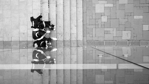 Directly above shot of friends sitting at staircase reflecting in glass