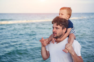 View of father and son on beach against sky