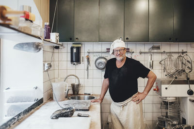 Portrait of senior baker standing by kitchen counter in bakery