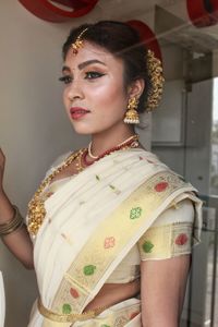 Woman wearing sari and jewelry while standing at home 