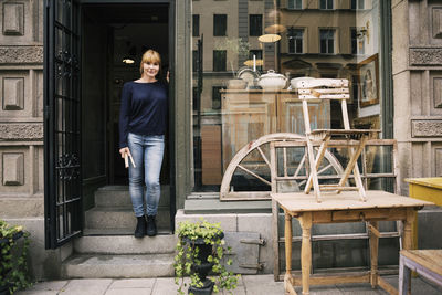 Female owner standing on entrance of antique shop