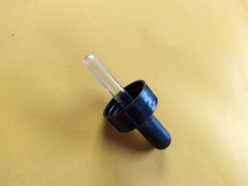 Glass dropper, to transfer small quantities of liquid, on yellow background.