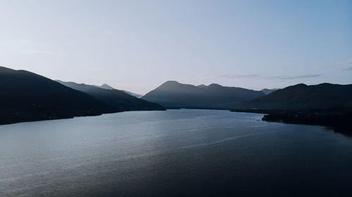 Scenic view of sea by mountains against sky