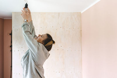 Woman standing against wall at home