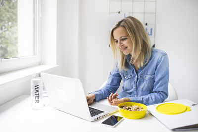 Young woman using phone while sitting on table