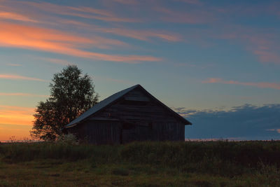 House on field against sky during sunset