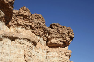 Low angle view of rock formation against clear blue sky at sahara desert