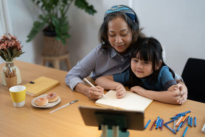 Grandmother teaching granddaughter at home