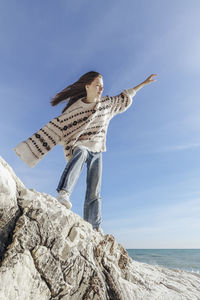 Carefree teenage girl balancing on rock at beach