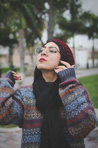 Young woman looking away while standing in park