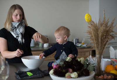 Mother cooking food with cute son in kitchen at home