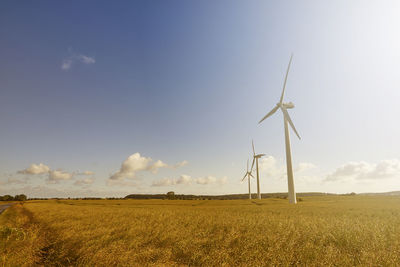 Wind turbines on field against sky