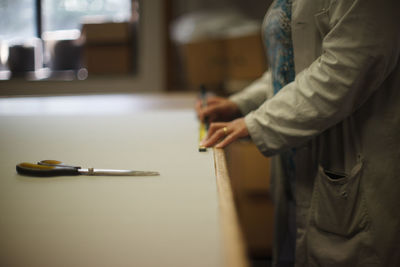 Midsection of man reading book on table