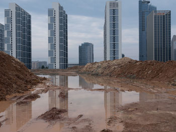 Reflection of buildings in city against sky