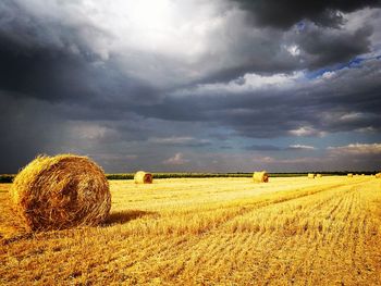 Hay bales on field against sky