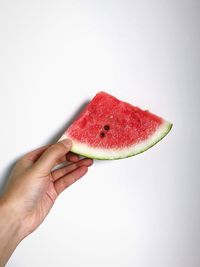 Close-up of hand holding strawberry over white background