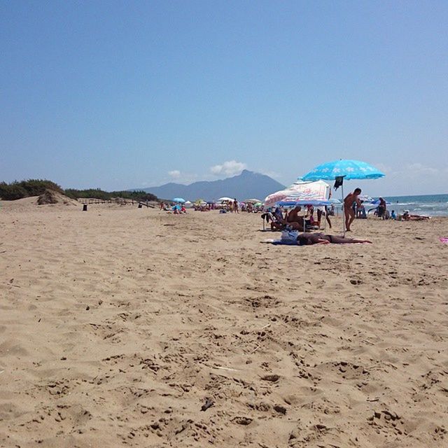 beach, sand, shore, sea, blue, clear sky, water, sky, copy space, tranquil scene, tranquility, vacations, incidental people, beach umbrella, scenics, nature, horizon over water, beauty in nature, summer, day