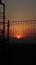 Silhouette fence against orange sky during sunset