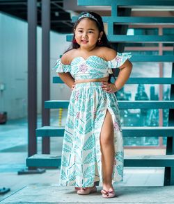 Cute girl in dress standing against steps