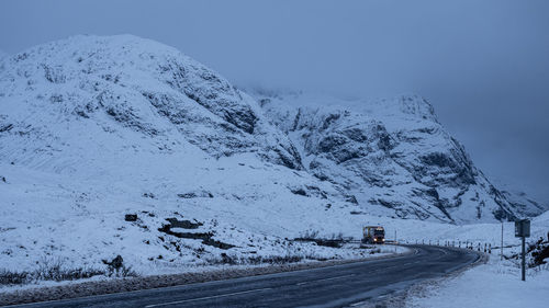 Road by snow covered mountain against sky