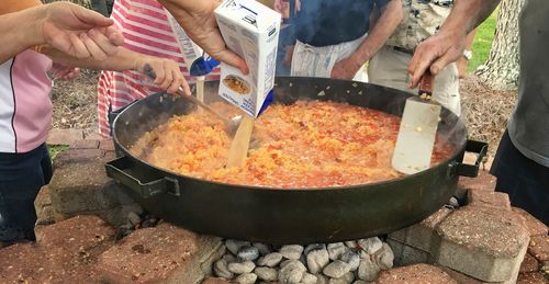 Midsection of people cooking food in yard