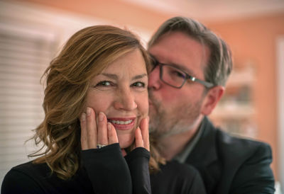 Man kissing smiling woman at home