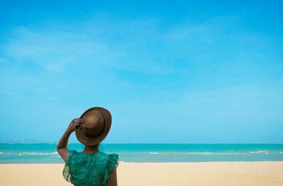 Rear view of boy on beach against sky