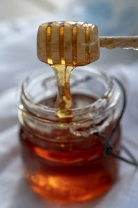 Close-up of honey in glass jar on table and wooden honey dipper