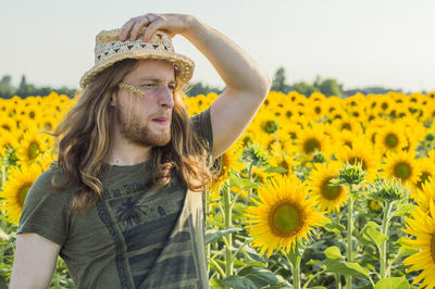 Portrait of young woman with sunflower standing on field