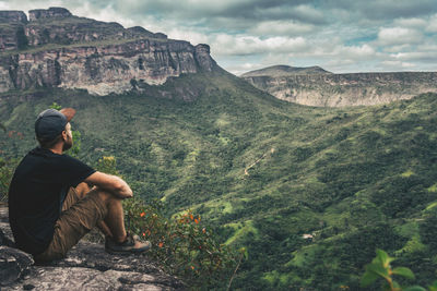 Man sitting on rock against mountains