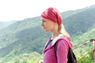 Portrait of young woman looking away against mountain