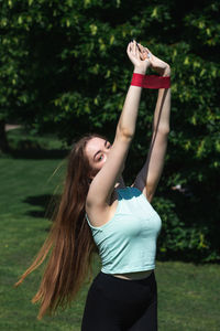 Young caucasian long-haired woman in sportswear is doing yoga in public park. outdoor workout. 