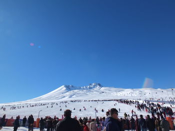 People at town square during winter against clear blue sky