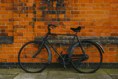 Bicycle parked against brick wall