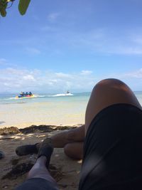 Man sitting on beach against sky