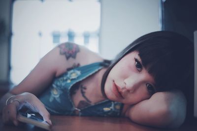 Portrait of woman lying on table at home