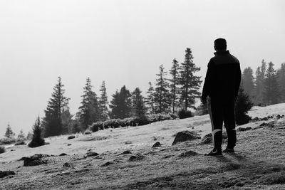 Rear view of man standing on land against sky