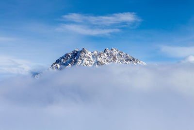 Snow covered rocks amid clouds