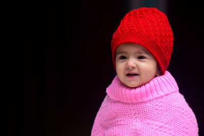 Indian baby girl wearing winter woolen poncho and knitted cap sitting and giving cute expressions