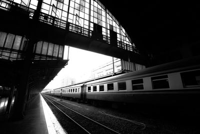 Black and white railway station platform where passenger trains are parked
