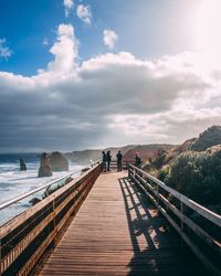 People on pier over sea against sky