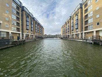 Canal amidst buildings in city against sky
