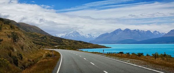 Road by mountains and lake against sky