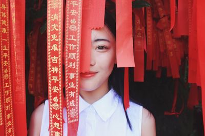 Close-up portrait of young woman amidst red ribbon
