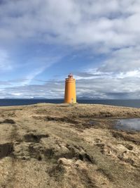 Lighthouse on street amidst buildings against sky