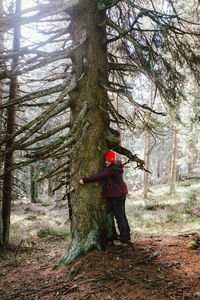 Man standing by tree in forest