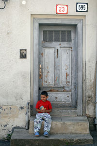 Portrait of boy sitting on door