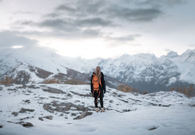 Rear view of person on snowcapped mountain against sky