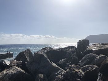 Rocks by sea against sky