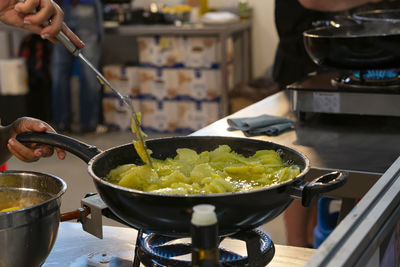 Woman frying potatoes to cook a typical food called tortilla de patatas.